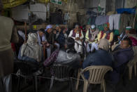 Farmers sit around a bonfire while blocking a major highway in a protest against new farm laws at the Delhi-Uttar Pradesh state border, India, Wednesday, Jan. 20, 2021. Farmers have been blockading highways connecting New Delhi to northern India for nearly seven weeks against new farm laws, obstructing transportation and dealing a blow to manufacturing and businesses in the north. Farmers fear the government will stop buying grain at minimum guaranteed prices and that corporations will then push prices down under the new laws. (AP Photo/Altaf Qadri)