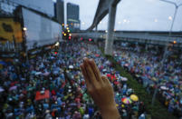 A pro-democracy protesters flashes a three-fingered salute during a protest in Bangkok, Thailand, Saturday, Oct. 17, 2020. The authorities in Bangkok shut down mass transit systems and set up roadblocks Saturday as Thailand capital faced a fourth straight day of determined anti-government protests. (AP Photo/Sakchai Lalit)