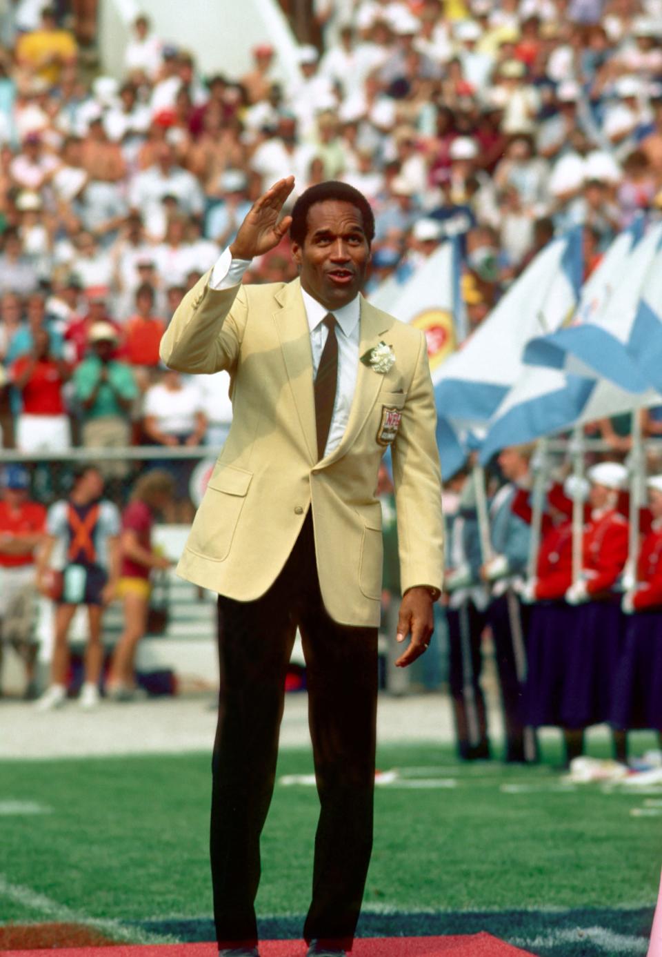 O.J. Simpson waves to fans as he is introduced at Fawcett Stadium during the Pro Football Hall of Fame Game, Aug. 3, 1985.