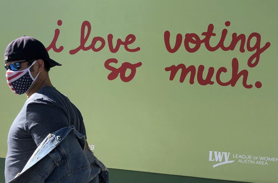 A man passes Jo's Coffee in Austin, Texas, where a mural outside has been repainted to read, "i love voting so much."