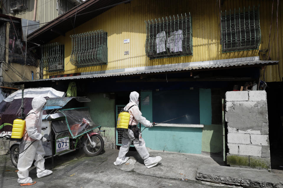 Health workers wearing protective suits disinfect at an area placed under stricter lockdown measures to curb the spread of COVID-19 in Caloocan city, Philippines on Friday, Aug. 14, 2020. The capital and outlying provinces is still under lockdown due to rising COVID-19 cases. (AP Photo/Aaron Favila)