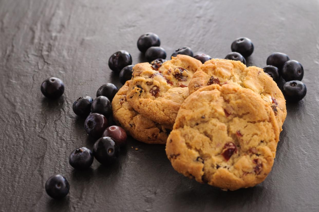 a few homemade cookies and blueberries on black background