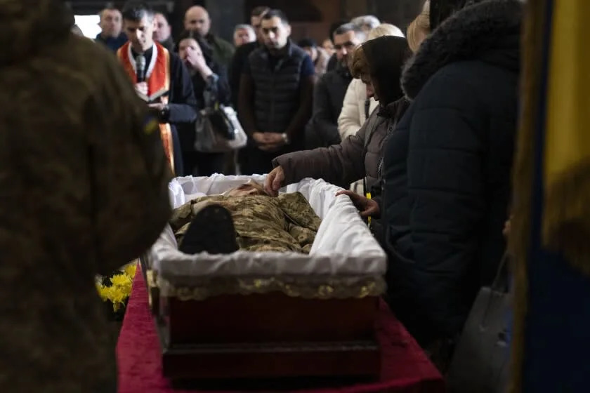 Mother stroking face of dead son in casket