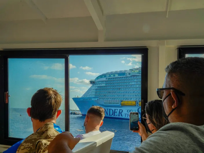 People look at a cruise ship from the window of a ferry