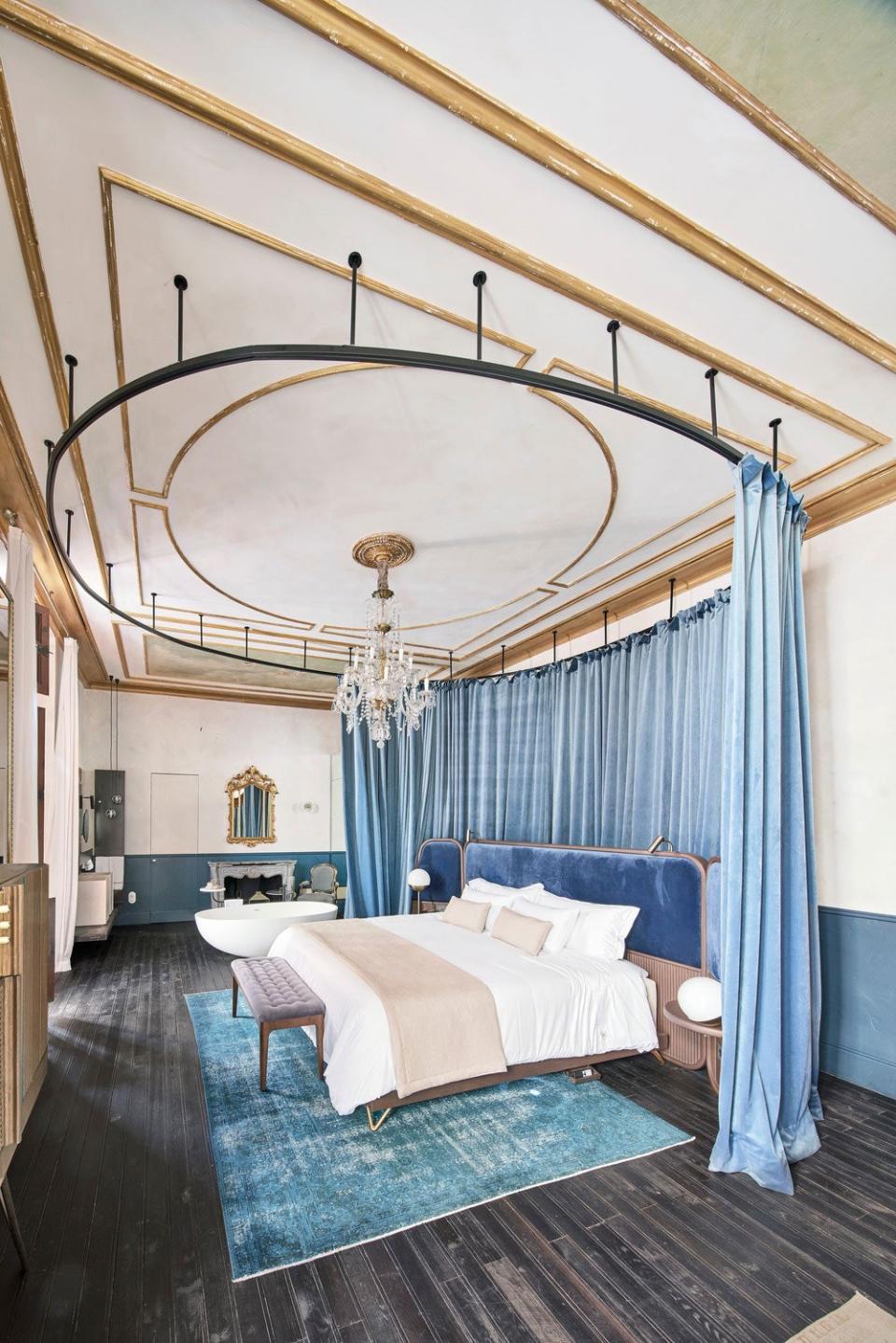 Thick light-blue velvet curtains encircle the bed, creating a sleeping cocoon separate from the bathroom.