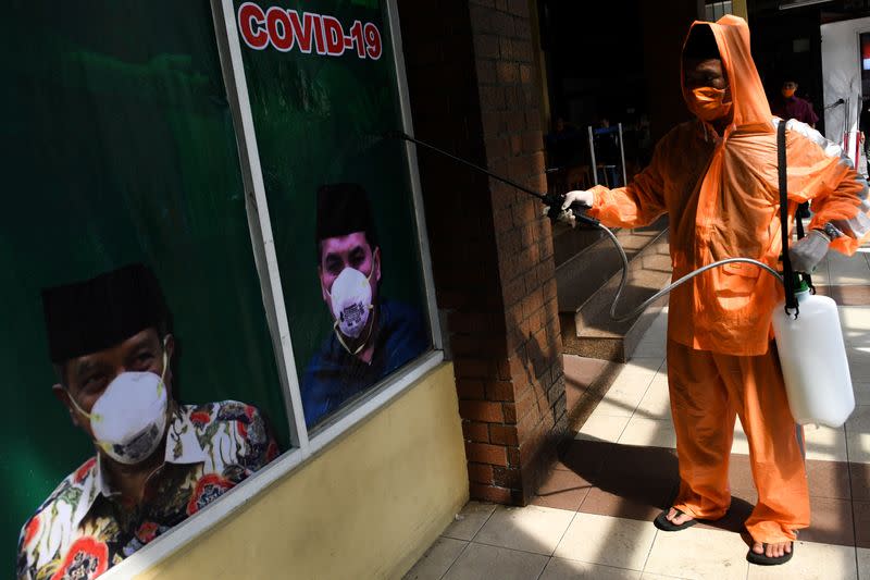 A worker sprays disinfectant at an office building, amid the coronavirus disease (COVID-19) outbreak in Jakarta