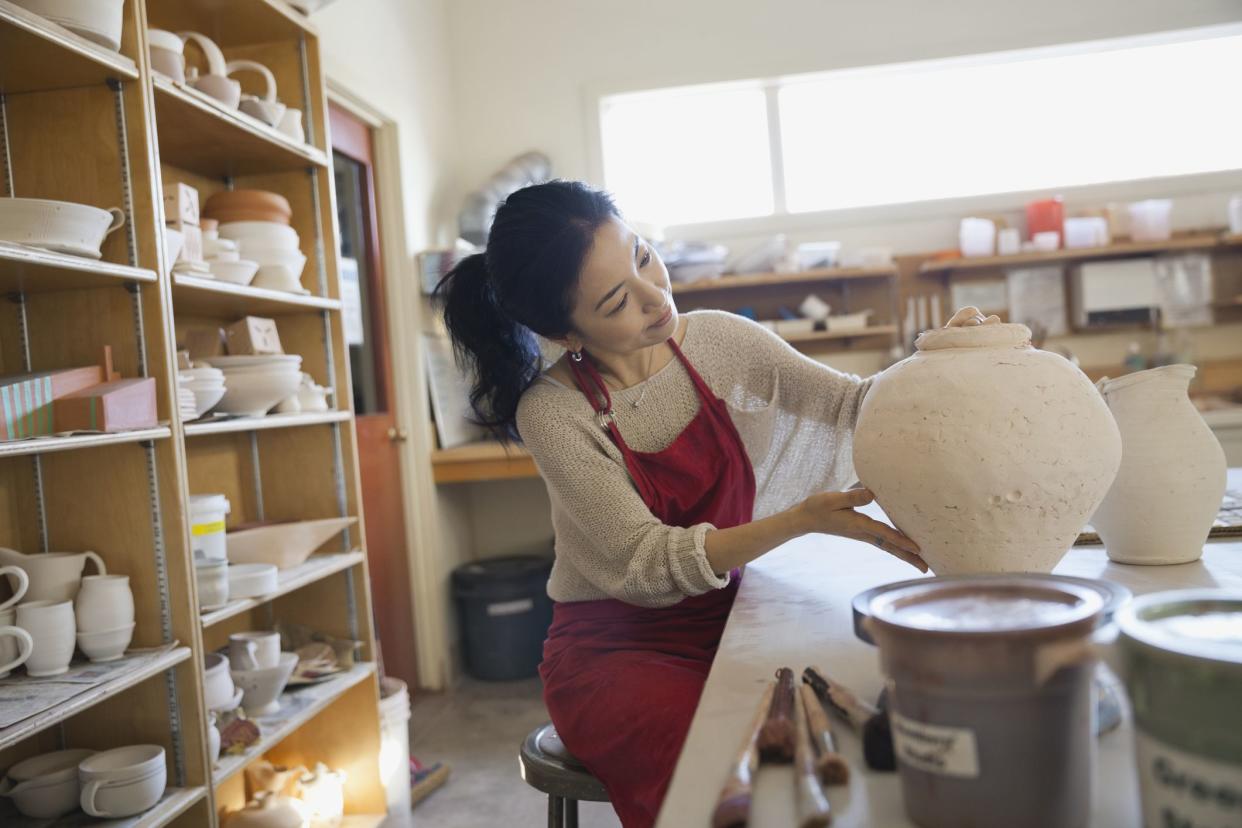 Female potter analyzing pot in studio