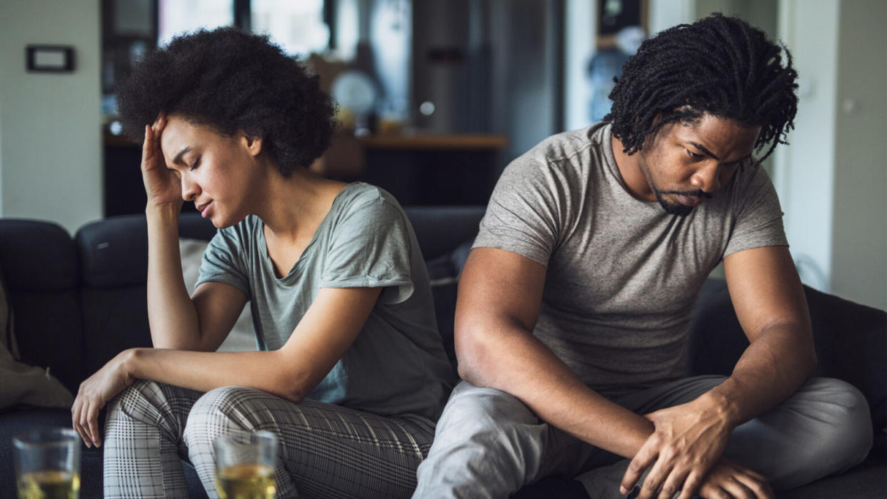 Deflecting is a common problem to deal with in a partner. If you're having trouble, take a look at this article. Pictured: A Black company sitting apart from one another, looking in opposite direction. A look of worry is on each person's face.