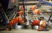 Workers use finishing trowels to plane fresh concrete on the track bed of the rails in the NEAT Gotthard Base tunnel near Erstfeld May 7, 2012. Crossing the Alps, the world's longest train tunnel should become operational at the end of 2016. The project consists of two parallel single track tunnels, each of a length of 57 km (35 miles) REUTERS/Arnd Wiegmann