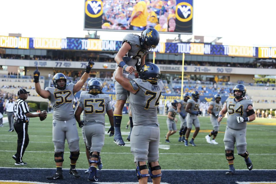 West Virginia offensive lineman Parker Moorer (52), quarterback Garrett Greene (6), offensive linemans James Gmiter (74) and Zach Frazier (54) celebrate after Greene scored a touchdown during the first half of an NCAA college football game against Long Island in Morgantown, W.Va., Saturday, Sept., 11, 2021. (AP Photo/Kathleen Batten)