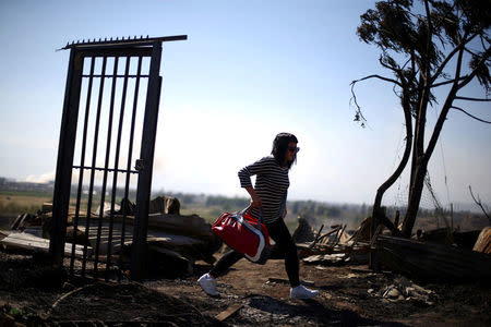 A woman walks between debris of shacks at an immigrants camp after an accidental fire in Santiago, Chile, December 14, 2016. Picture taken December 14, 2016. REUTERS/Ivan Alvarado