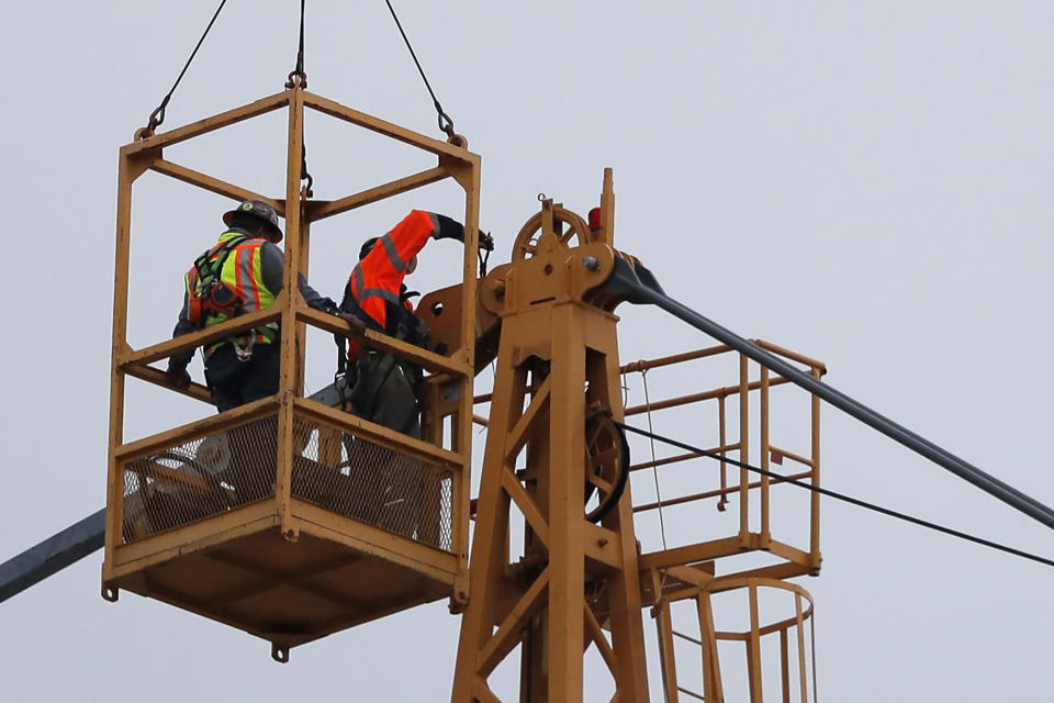 Workers in a bucket hoisted by a crane begin the process of preparing the two unstable cranes for implosion at the collapse site of the Hard Rock Hotel, which underwent a partial, major collapse while under construction last Sat., Oct., 12, in New Orleans, Friday, Oct. 18, 2019. Plans have been pushed back a day to bring down two giant, unstable construction cranes in a series of controlled explosions before they can topple onto historic New Orleans buildings, the city's fire chief said Friday, noting the risky work involved in placing explosive on the towers. (AP Photo/Gerald Herbert)