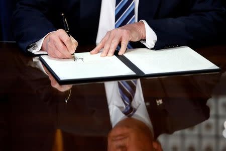 U.S. President Donald Trump signs an executive order during a ceremony with Treasury Secretary Steve Mnuchin at the Treasury Department in Washington, U.S., April 21, 2017. REUTERS/Aaron P. Bernstein