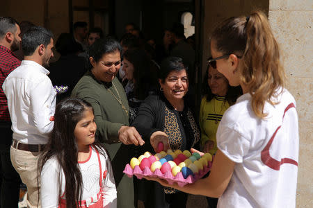 Believers wait to receive a painted egg during celebrations after the Easter Mass in Mar Gewargis (St George) Chaldean Catholic church, which was damaged by Islamic State militants, in the town of Tel Esqof, Iraq, April 16, 2017. REUTERS/Marko Djurica