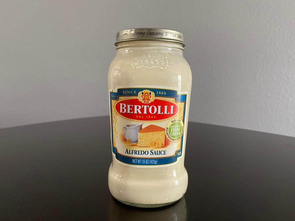Jar of Bertolli Alfredo sauce on a black table
