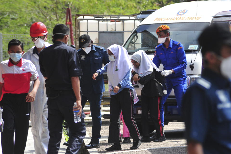 Emergency personnel help students school evacuate after toxic chemical spill in Pasir Gudang, Johor, on 13 March 2019. (PHOTO: AP/Thomas Yong)