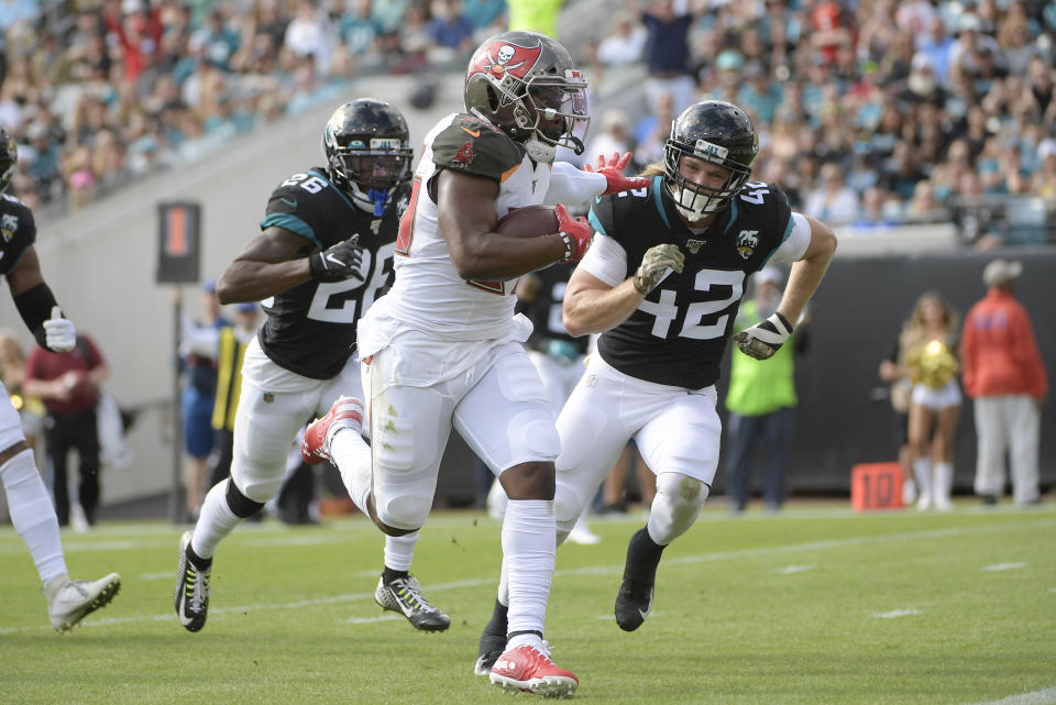 Tampa Bay Buccaneers running back Peyton Barber, center, runs for yardage past Jacksonville Jaguars free safety Jarrod Wilson (26) and defensive back Andrew Wingard (42) during the first half of an NFL football game, Sunday, Dec. 1, 2019, in Jacksonville, Fla. (AP Photo/Phelan M. Ebenhack)