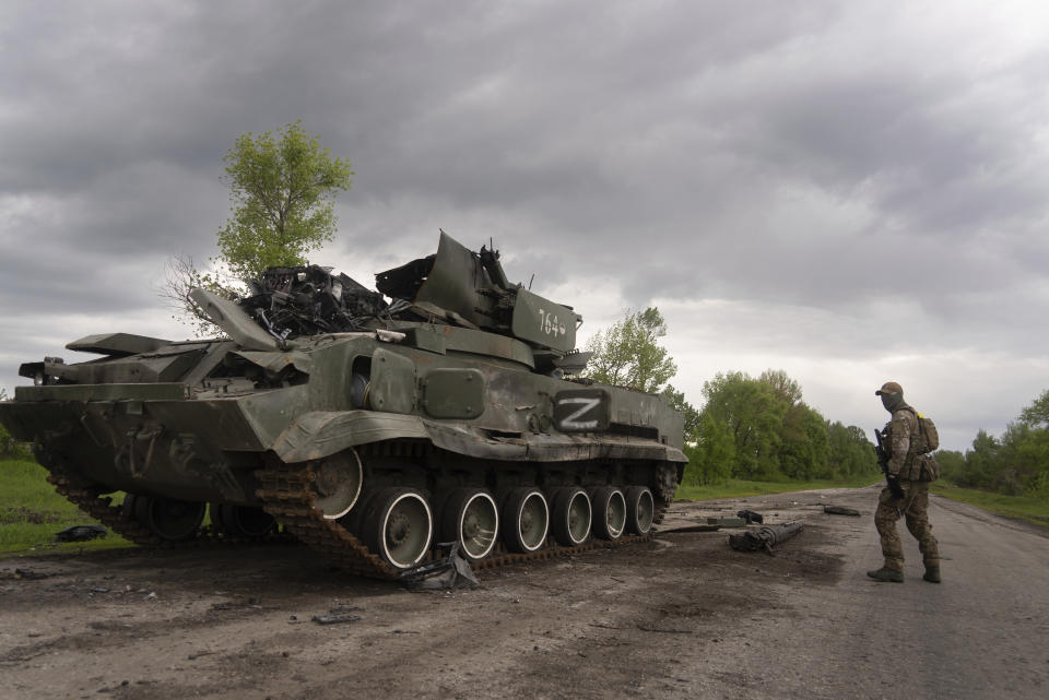 Ukrainian serviceman walks past a blown Russian APC near Kutuzivka, north of Kharkiv, east Ukraine, Sunday, May 15, 2022. (AP Photo/Mstyslav Chernov)