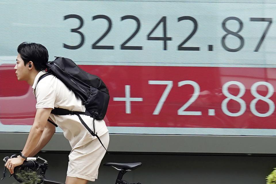 A person rides a bicycle in front of an electronic stock board showing Japan's Nikkei 225 index at a securities firm Tuesday, Aug. 29, 2023, in Tokyo. Asian shares mostly rose Tuesday as markets shift their attention from the U.S. Federal Reserve to earnings and economic reports.(AP Photo/Eugene Hoshiko)