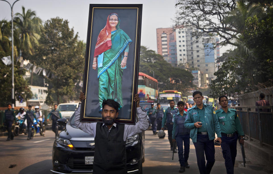 FILE- A supporter of Bangladesh Awami League party carries a giant portrait of Bangladesh Prime Minister Sheikh Hasina during an election rally in Dhaka, Bangladesh, Dec. 27, 2018. The elections in Bangladesh are all about one person: Prime Minister Sheikh Hasina. Analysts predict that since the main opposition party is staying out of the Jan. 7 vote, the 76-year-old leader is practically guaranteed her fifth term in office.(AP Photo/Anupam Nath, File)