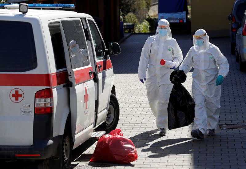 Members of Czech Army wearing protective gear carry samples in Brno