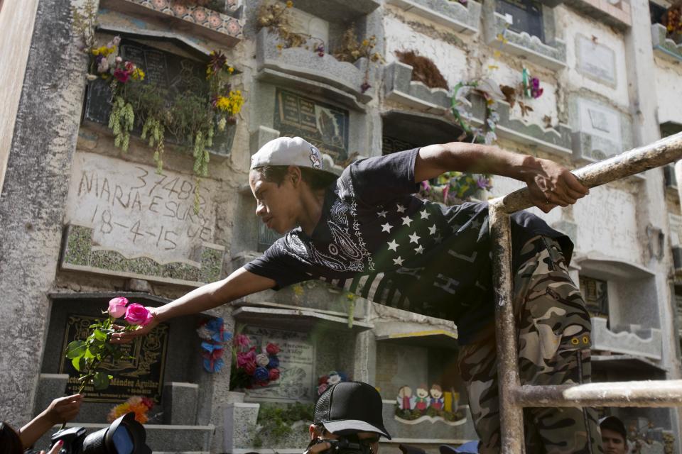 A worker is handed a couple of roses for the grave of 14-year-old Madelyn Patricia Hernandez Hernandez, a girl who died in a fire at the Virgin of the Assumption Safe Home, at the Guatemala City's cemetery, Friday, March 10, 2017. Families began burying some of the 36 girls killed in a fire at an overcrowded government-run youth shelter in Guatemala as authorities worked to determine exactly what happened. (AP Photo/Moises Castillo)