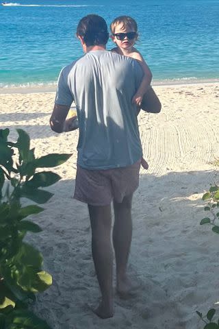 <p>Olivia Munn/Instagram</p> John Mulaney is seen carrying his son Malcolm on the beach