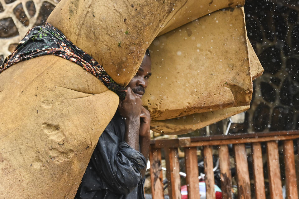 A man carries his belongings at a displacement center in Blantyre, Malawi Tuesday March 14, 2023. The unrelenting Cyclone Freddy that is currently battering southern Africa has killed more than 50 people in Malawi and Mozambique since it struck the continent for a second time on Saturday night. (AP Photo/Thoko Chikondi)