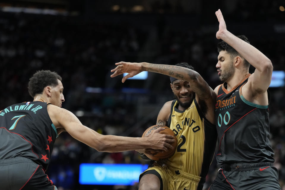 Toronto Raptors forward Jalen McDaniels (2) drives between Washington Wizards forward Patrick Baldwin Jr. (7) and Wizards forward Tristan Vukcevic (00) during the first half of an NBA basketball game in Toronto Sunday, April 7, 2024. (Frank Gunn/The Canadian Press via AP)