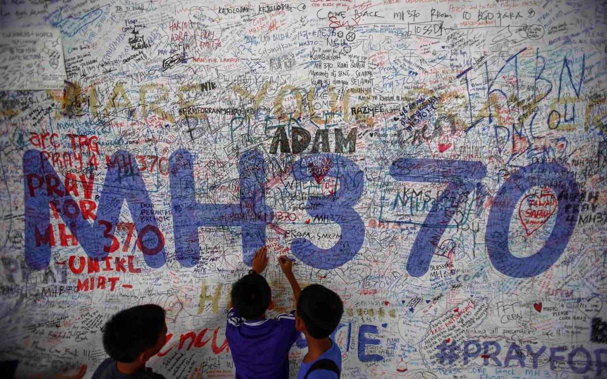 Children write messages for the passengers of MH370 on a wall in Kuala Lumpur airport - Reuters