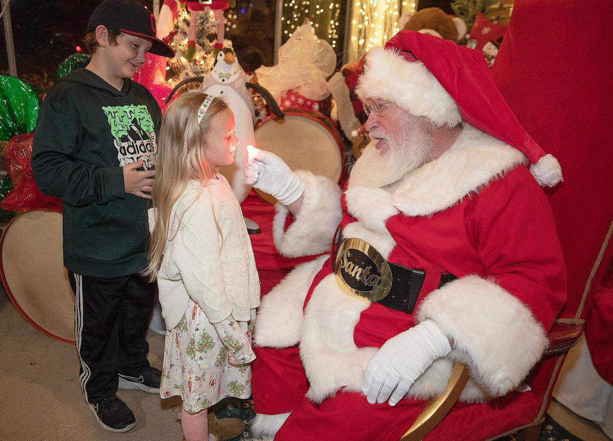 Santa Claus checks Lucy Molyneaux, 4, of Plain Township to see if she was good girl with his Rudolph nose along with her brother Madden Molyneaux, 8, at the 32nd annual Holly Pine Lane Christmas event at the Canton Garden Center in Stadium Park.