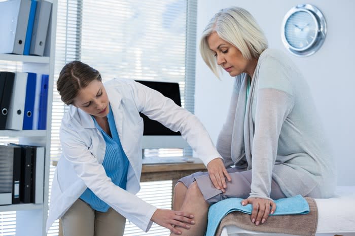 A doctor examining the knee of a patient.