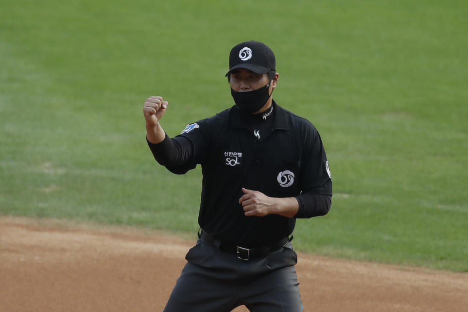 First base umpire Kim Seon-soo, wearing a mask as a precaution against the coronavirus, makes a call during the KBO league baseball game between KT Wiz and Doosan Bears in Seoul, South Korea, Sunday, Aug. 16, 2020. Fans are banned once again from professional baseball and soccer games, which had just begun to slowly bring back spectators in late July. (AP Photo/Lee Jin-man)
