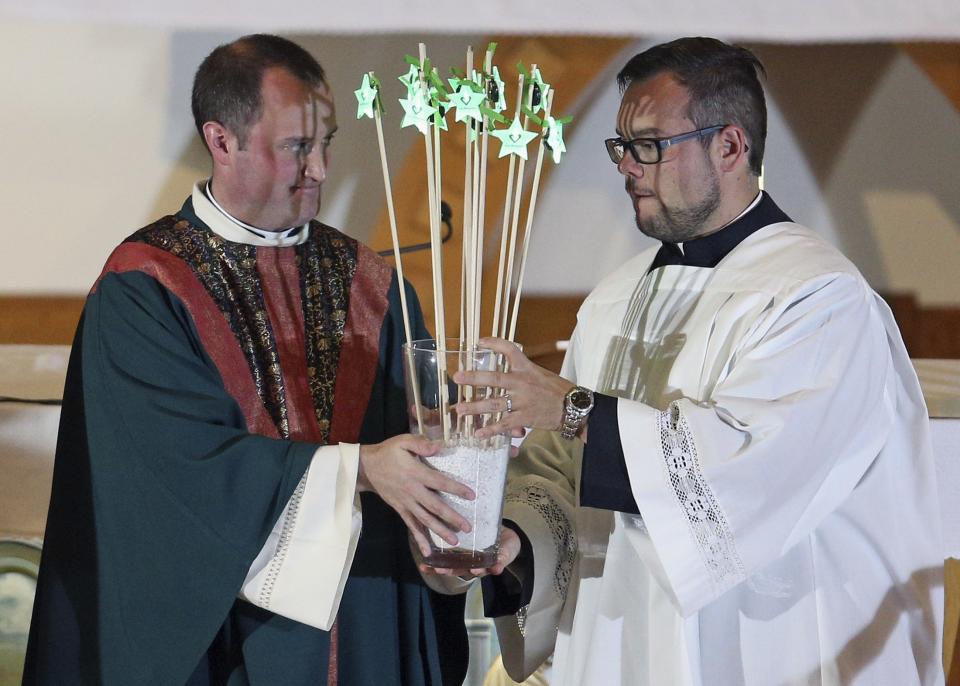 Priest Steve Lemay gives illuminated stars to colleague during Messe Reconfort at Sainte-Agnes church in Lac-Megantic