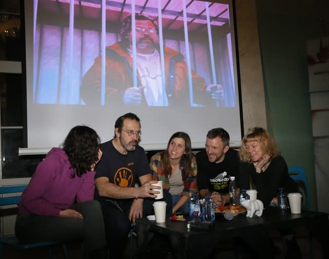 From left: Greenpeace International activists Faiza Oulahsen of Netherlands, Dima Litvinov of Sweden, Camila Speziale of Argentina, Phiip Ball of the United Kingdom and Sini Saarela of Finland attend their meeting with residents of St.Petersburg, Russia, Monday, Dec. 23, 2013, with a projection of image of Greenpeace International activist Roman Dolgov of Russia standing in a cage in the background. Russia's parliament last Wednesday passed an amnesty bill that will likely apply to the 30-member crew of a Greenpeace ship detained after an Arctic protest, but it wasn't immediately clear if and when the activists would be allowed to leave the country. (AP Photo/Dmitry Lovetsky)