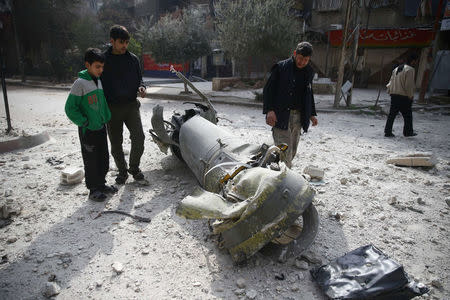 People inspect missile remains in the besieged town of Douma, in eastern Ghouta, in Damascus, Syria, February 23, 2018. REUTERS/Bassam Khabieh
