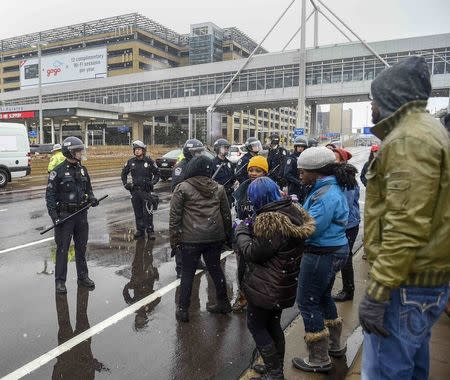 Police keep a group of Black Lives Matter protesters to the side of the road after they shut down the main road to the Minneapolis St. Paul Airport following a protest at the Mall of America in Bloomington, Minnesota December 23, 2015. REUTERS/Craig Lassig