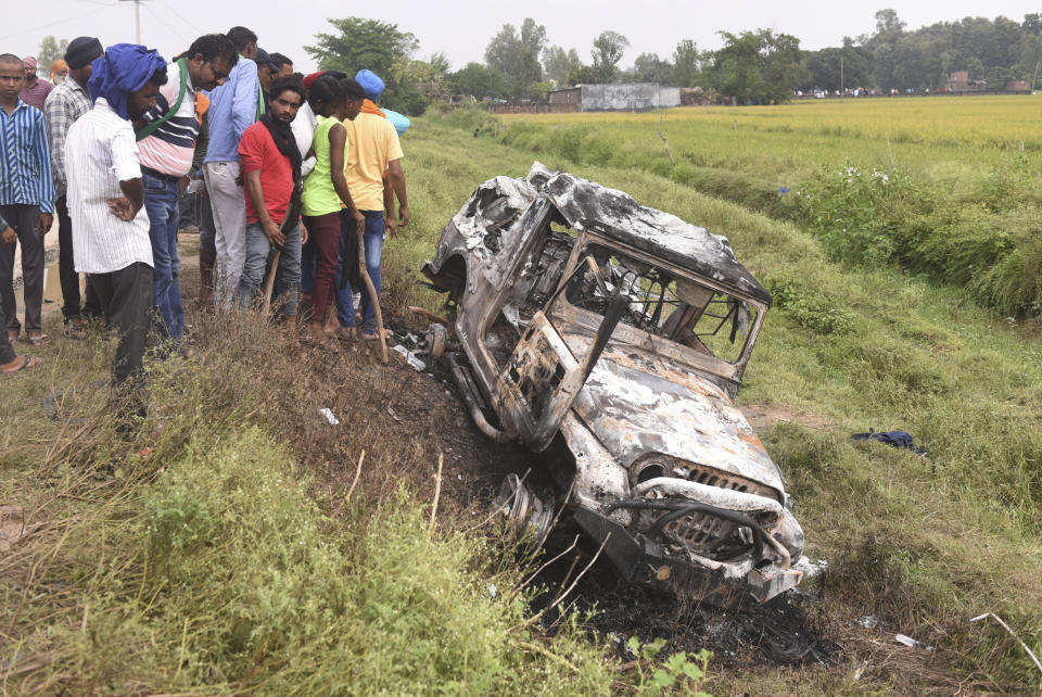 Villagers watch a burnt car which ran over and killed farmers on Sunday, at Tikonia village in Lakhimpur Kheri, Uttar Pradesh state, India, Monday, Oct. 4, 2021. Indian police on Saturday, Oct. 9, arrested the son of a junior minister in Prime Minister Narendra Modi’s government as a suspect days after nine people were killed in a deadly escalation of yearlong demonstrations by tens of thousands of farmers against contentious agriculture laws in northern India, a police officer said. (AP Photo)