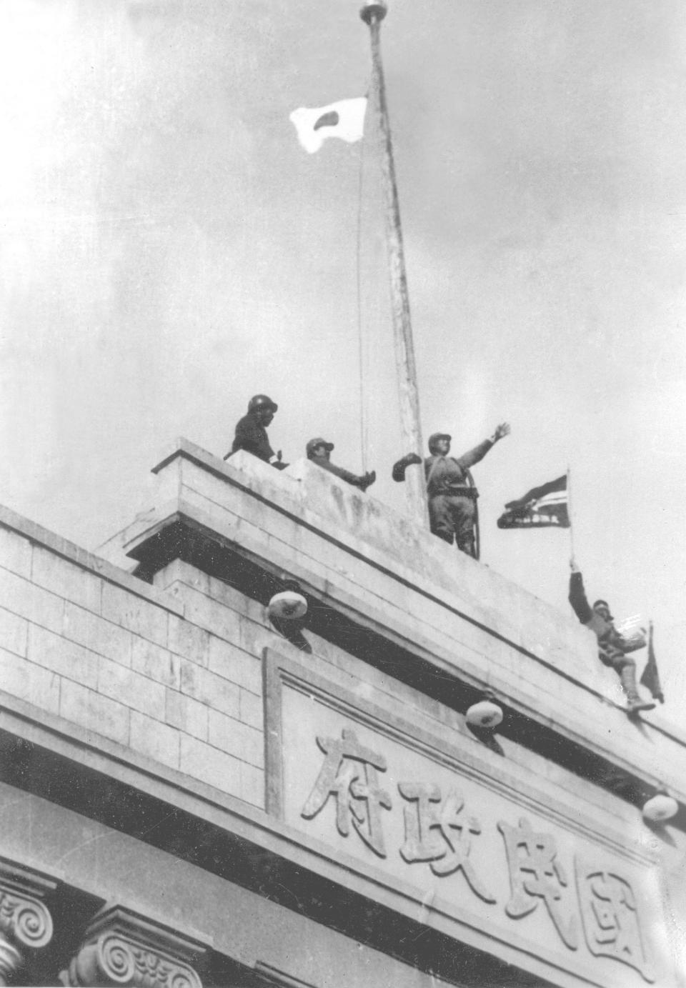 FILE - In this December, 1937, file photo, Japanese soldiers cheer as they hoist their flag from the roof of the central government building after they seized Nanking in the Second Sino Japanese War. China and an international postwar tribunal said at least 200,000 civilians were killed by Japanese troops in a weekslong frenzy of murder, rape and arson after Nanking, then China's capital, fell to Japan on Dec. 13, 1937. (AP Photo, File)