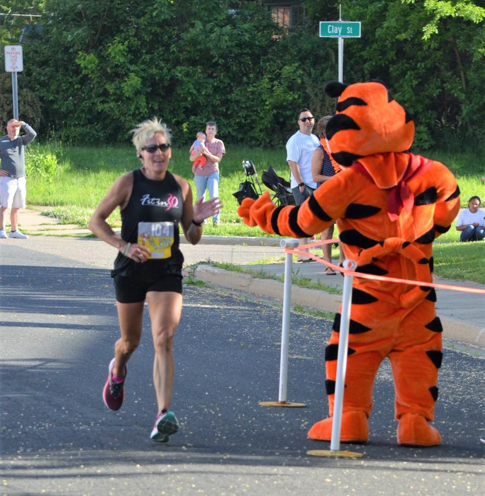 Battle Creek's Mary Faber is congratulated by Tony the Tiger as she is the first female finisher in the 5K at the Cereal City Classic on Saturday.