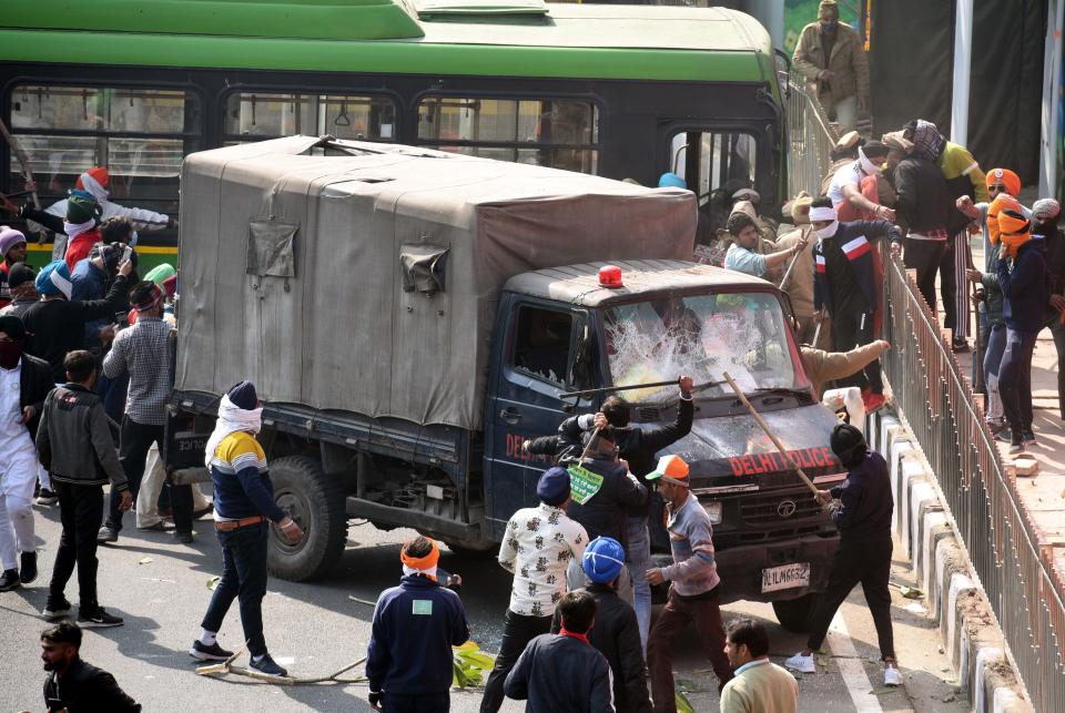 NEW DELHI, INDIA - JANUARY 26: Protesting farmers damaging a police vehicle after a tractor rally entered the city on Republic Day at ITO on January 26, 2021 in New Delhi, India. Major scenes of chaos and mayhem at Delhi borders as groups of farmers allegedly broke barricades and police check posts and entered the national capital before permitted timings. Police used tear gas at Delhi's Mukarba Chowk to bring the groups under control. Clashes were also reported at ITO, Akshardham. Several rounds of talks between the government and protesting farmers have failed to resolve the impasse over the three farm laws. The kisan bodies, which have been protesting in the national capital for almost two months, demanding the repeal of three contentious farm laws have remained firm on their decision to hold a tractor rally on the occasion of Republic Day.(Photo by Arvind Yadav/Hindustan Times via Getty Images)