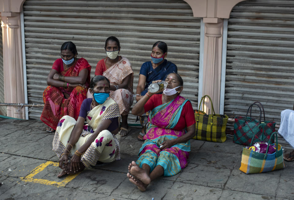 Daily wage laborers wearing masks as a precaution against the coronavirus wait to be hired for work by a roadside in Kochi, Kerala state, India, Friday, Nov. 20, 2020. India's total number of coronavirus cases since the pandemic began crossed 9 million on Friday. (AP Photo/R S Iyer)