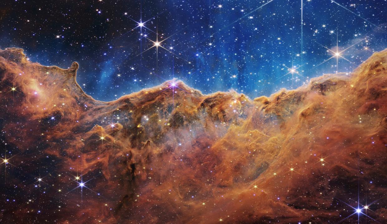 July 12, 2022: In this handout photo provided by NASA, a landscape of mountains and valleys speckled with glittering stars is actually the edge of a nearby, young, star-forming region called NGC 3324 in the Carina Nebula, on July 12, 2022 in space. Captured in infrared light by NASA's new James Webb Space Telescope, this image reveals for the first time previously invisible areas of star birth.