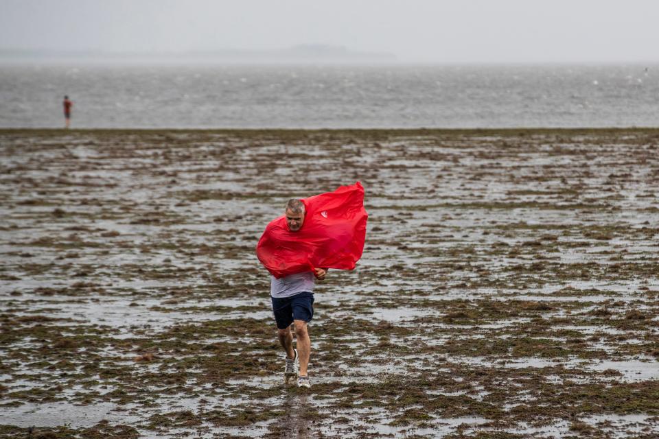 Curious sightseers walk in the receding waters of Tampa Bay due to the low tide and tremendous winds from Hurricane Ian in Tampa, Fla., Wednesday, Sept. 28, 2022. (Willie J. Allen Jr./Orlando Sentinel via AP)