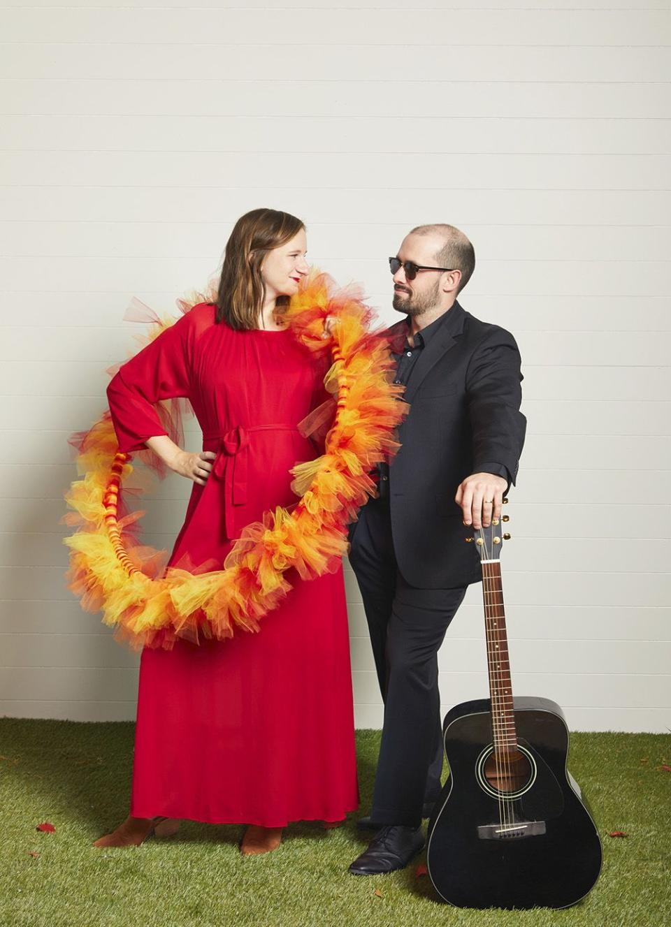 woman wearing red dress and fire hula hoop and man wearing black suit for ring of fire couple costume