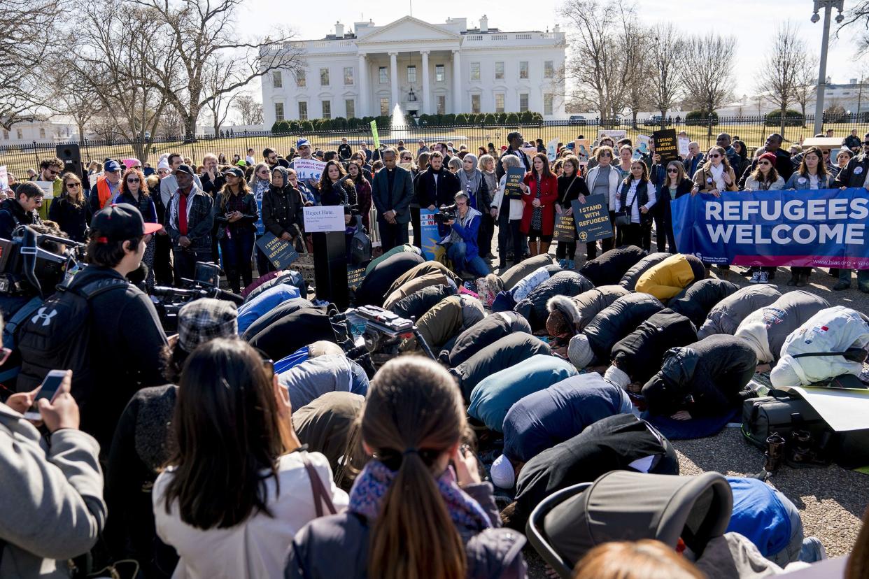 In this Jan. 27, 2018 photo, supporters surround a group who perform the Islamic midday prayer outside the White House during a rally on the one-year anniversary of the Trump administration's first partial travel ban on citizens from seven Muslim-majority countries. 