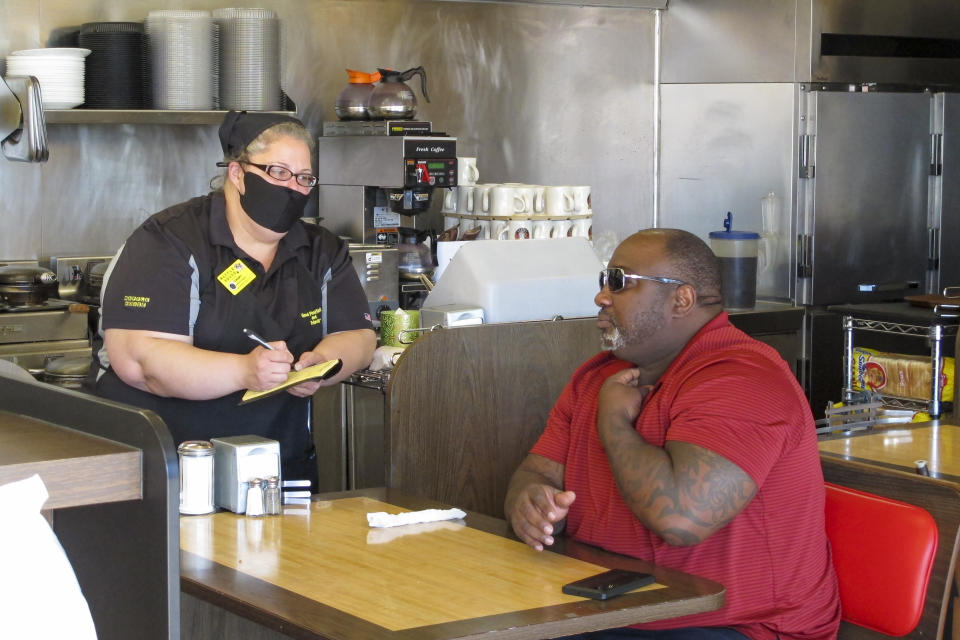 Corey Brooks, right, orders food at a Waffle House restaurant in Savannah, Georgia, on Monday, April 27, 2020. Restaurants statewide were allowed to resume dine-in service with restrictions after a month of being limited to takeout orders because of the coronavirus. (AP Photo/Russ Bynum)