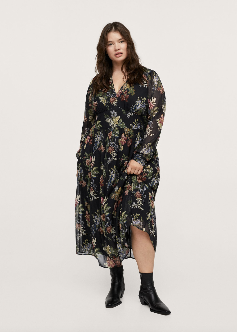 plus size model with brown hair posing in black booties and floral maxi dress