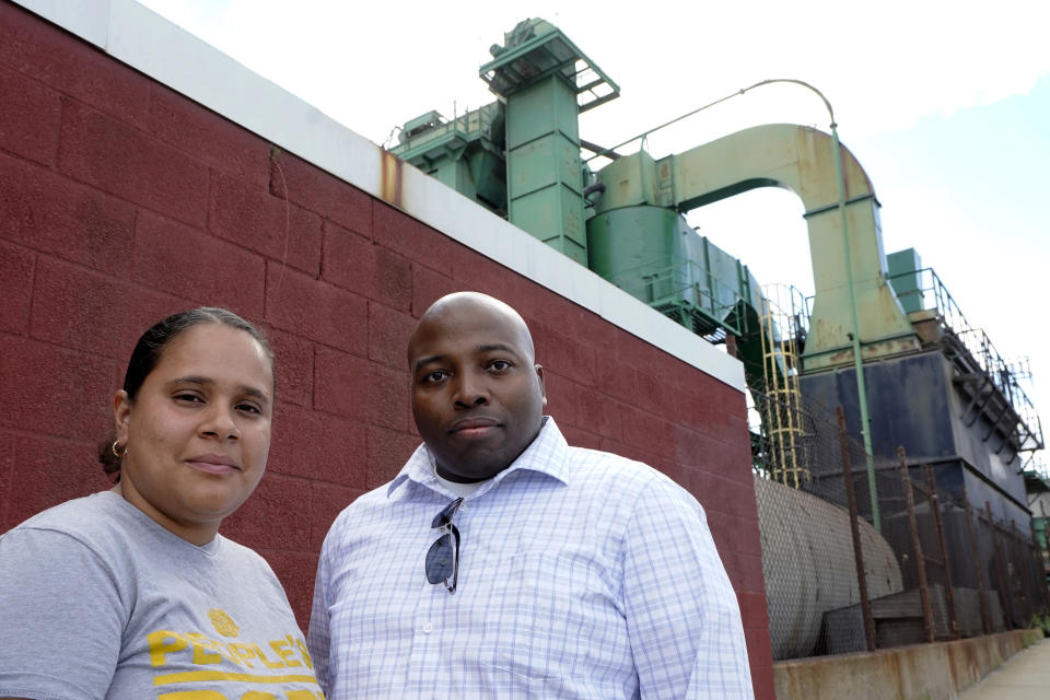 Monica Huertas, left, and Dwayne Keys, right, both of Providence, R.I., stand for a photograph in a neighborhood in Providence that features industrial businesses, Thursday, Aug. 18, 2022. In Rhode Island, state lawmakers considered a bill this year to exempt such facilities from solid waste licensing requirements. Keys said it’s unfair that he and his neighbors always have to be on guard for proposals like these, unlike residents in some of the state’s wealthy, white neighborhoods. (AP Photo/Steven Senne)