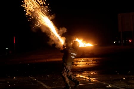 A riot policeman shoots tear gas towards demonstrators (not pictured) during a union strike of Chuquicamata copper mine, one of the world's largest, in Calama